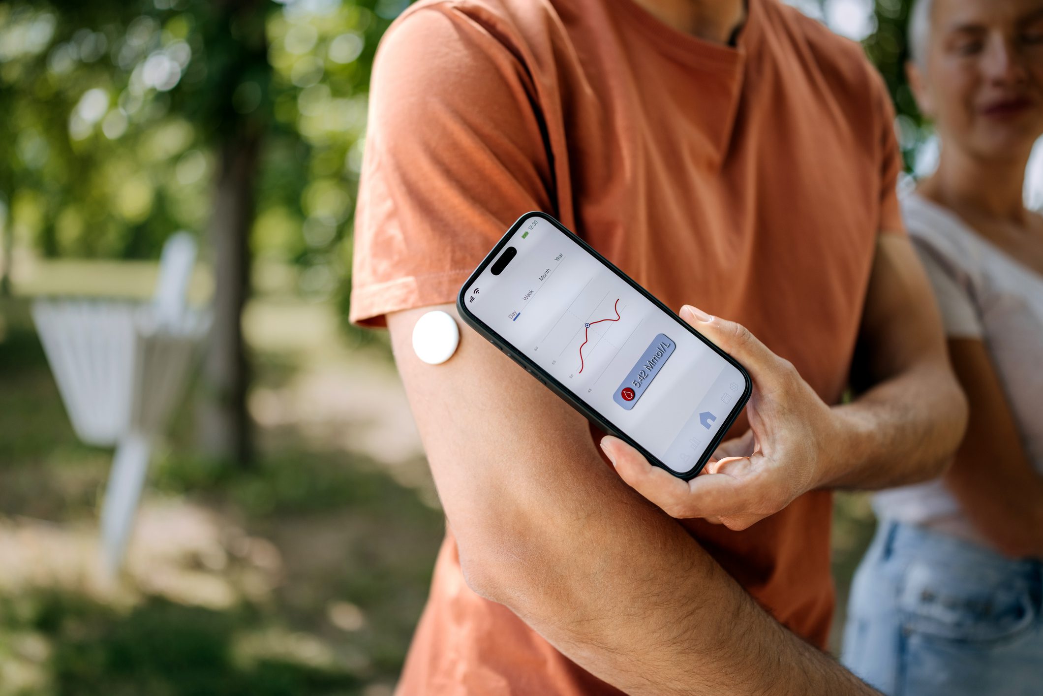 Person using a smartphone app to scan a patch on their arm outdoors.